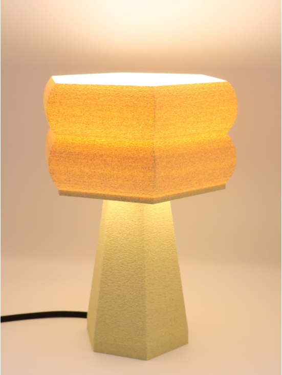 Lampe à poser design Thaïs granit vanille allumée, mise en scène studio, câble noir visible.