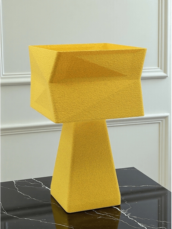 Lampe à poser design Adèle granit jaune sur table noire marbrée, ambiance chic et lumineuse, mur blanc mouluré.