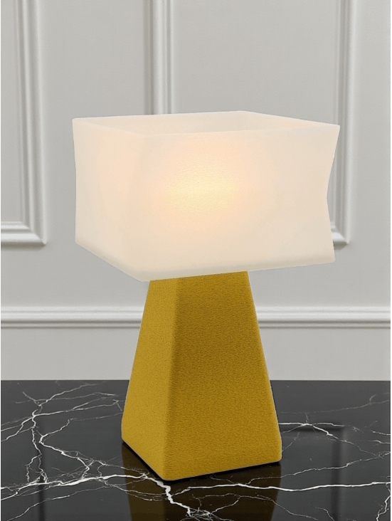 Lampe à poser design Juliane granit jaune allumée sur table noire marbrée, lumière douce, ambiance chic.