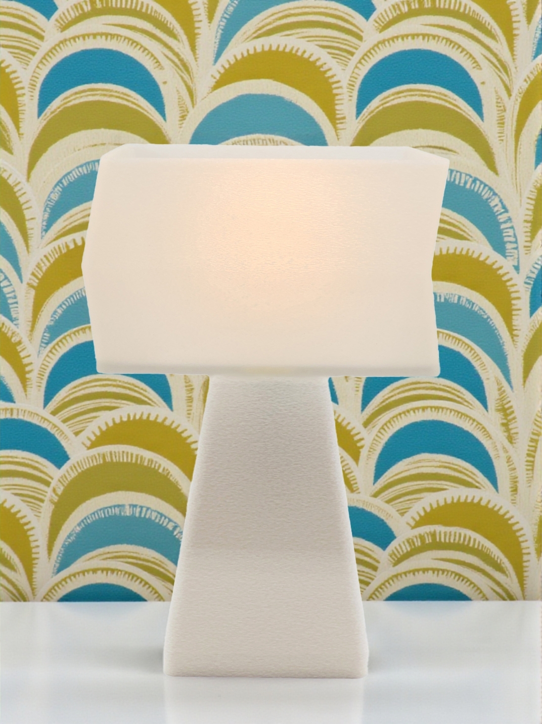 Lampe à poser Juliane Pop blanche allumée, abat-jour blanc lumineux, ambiance rétro avec décor éventails bleu et kaki.