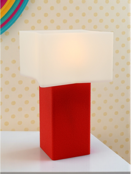 Lampe à poser Priscilla Pop Essentiel rouge allumée, abat-jour blanc lumineux, ambiance rétro avec mur à pois beige.