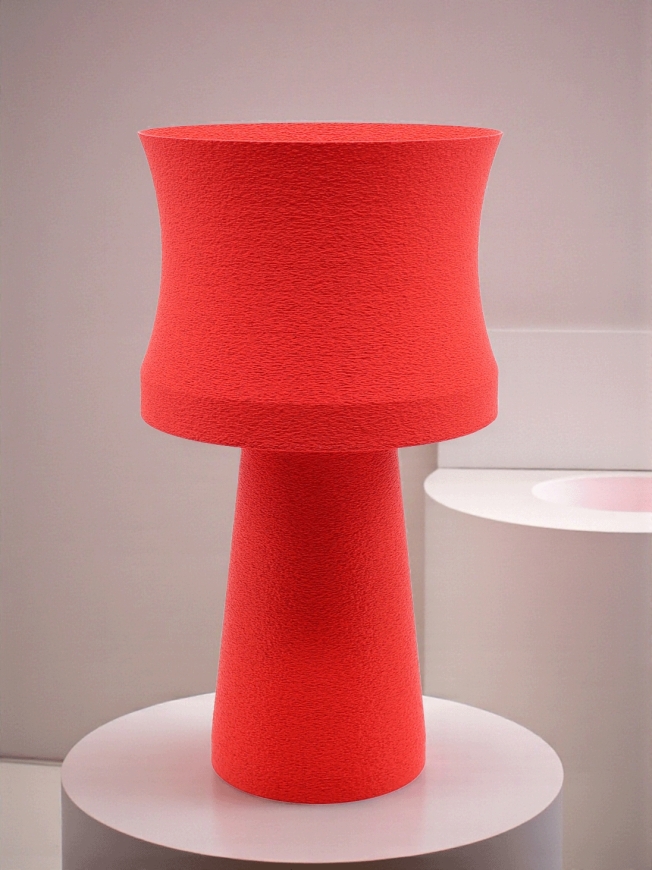Lampe à poser design Agathe granit rouge sur socle rond blanc, ambiance douce et minimaliste, mur clair.