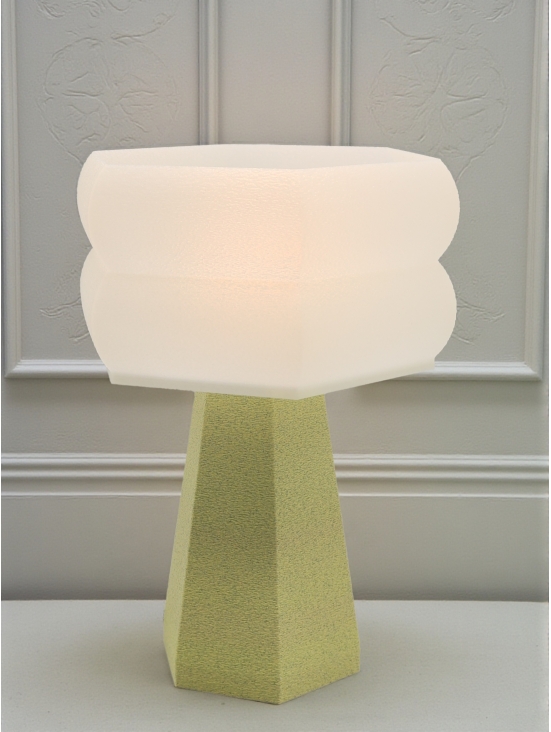 Lampe à poser design Aline granit vanille allumée, lumière douce, ambiance élégante sur mur mouluré clair.