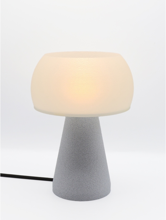 Lampe à poser design Annie granit pierre allumée, abat-jour crème, ambiance studio lumineuse, câble noir.