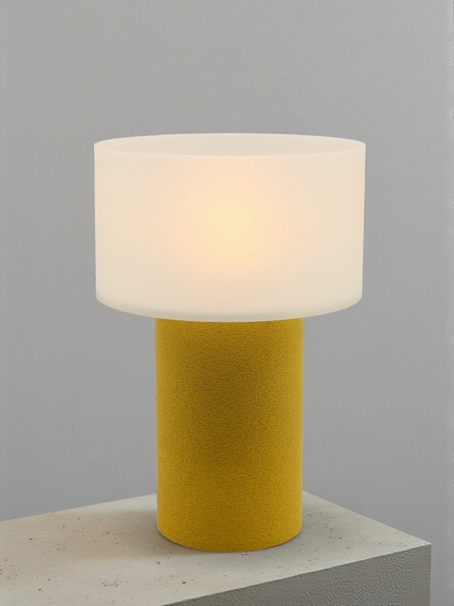 Lampe à poser design Clarisse granit jaune allumée sur socle béton, lumière douce, ambiance minimaliste.