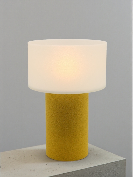 Lampe à poser design Clarisse granit jaune allumée sur socle béton, lumière douce, ambiance minimaliste.