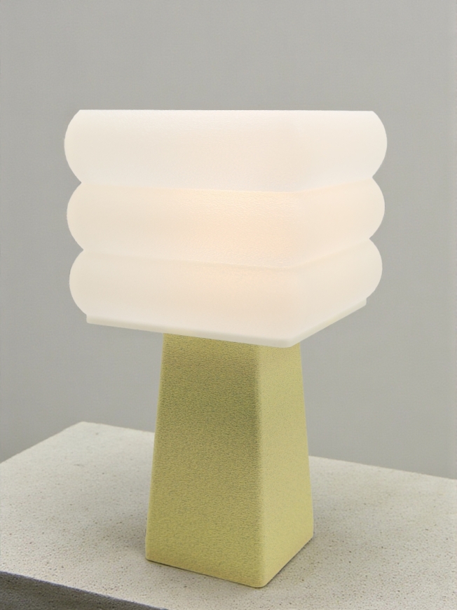 Lampe à poser design Isabelle granit vanille allumée sur socle béton, lumière douce, ambiance minimaliste.