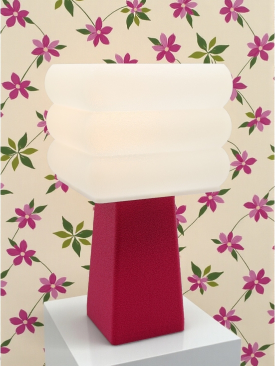 Lampe à poser Isabelle Pop magenta allumée, abat-jour blanc à paliers lumineux, ambiance rétro avec papier peint fleuri rose.
